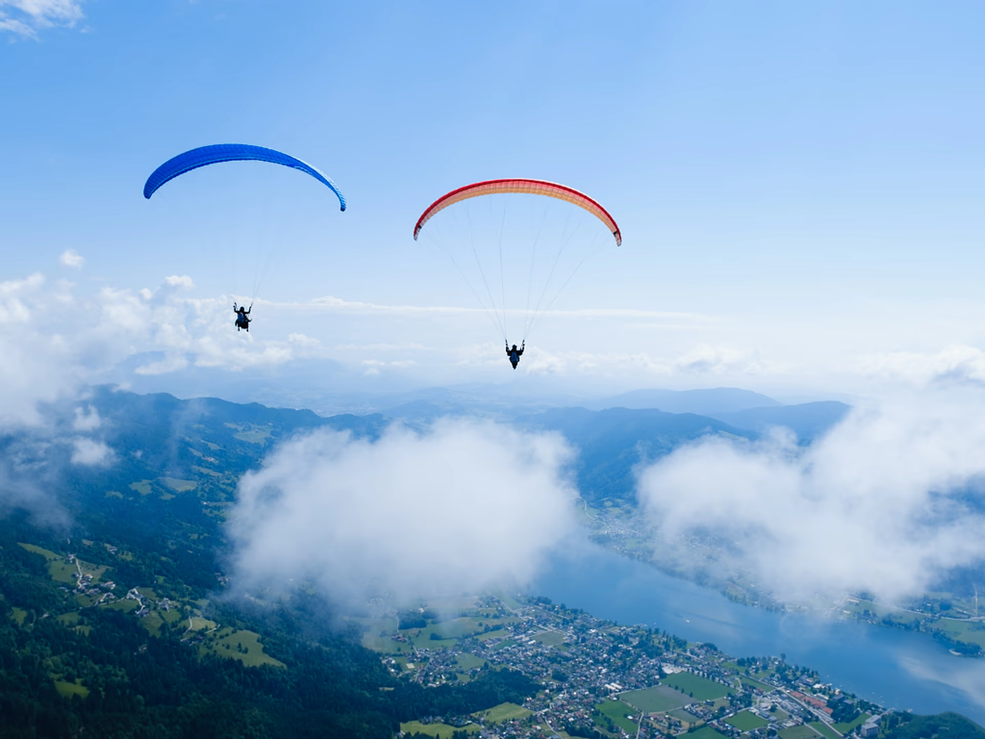Zwei Tandemschirme nebeneinander über dem Ossiacher See